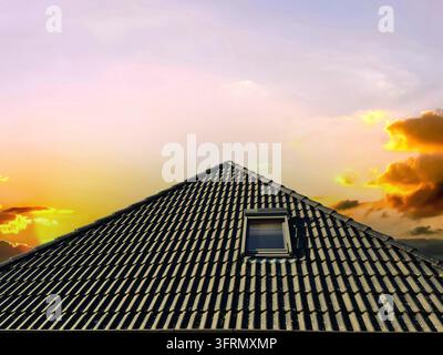Tramonto colorato. Finestra a tetto aperto in stile velluto con tegole nere Foto Stock