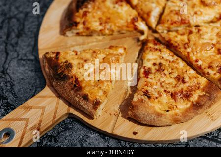 Pizza appena sfornata affettata su un tagliere di legno Foto Stock
