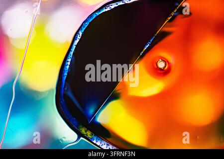 Composizione astratta vibrante di luce arancione, gialla, blu e magenta luminose rifratte attraverso vetro traslucido con forme scure curve e un B morbido Foto Stock