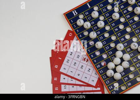 Elementi di gioco del bingo su una superficie bianca, con tabella delle chiamate, carte bingo e palline numerate Foto Stock