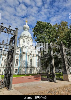 Grande edificio bianco Cattedrale Smolny con una cupola blu. L'edificio Tempio di Maria Maddalena è circondato da una recinzione. La recinzione ha un cancello che è aperto Foto Stock
