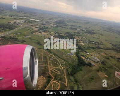 Un'ala di aereo rosa è visibile in volo. L'ala è sul lato sinistro dell'immagine a Johannesburg in Sudafrica Foto Stock
