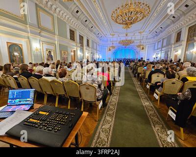 Mosca - 19 dic. 2023: Un grande pubblico è seduto in una grande sala. Un produttore di suoni per tastiera è su un tavolo di fronte al pubblico nella Camera della Cattedrale. Gli spettatori di un concerto corale cantano un'aria Foto Stock