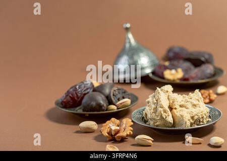 Halva di tahini, datteri, pistacchi serviti su piatti tradizionali orientali, messa a fuoco selettiva. Concetto di dolci tradizionali orientali per il Ramadan Foto Stock