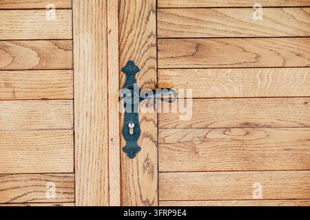 Maniglia di porta in ferro ornata e serratura con serratura montate al centro di un pannello di porta in quercia. Concetto di arredamento per la casa. Foto Stock