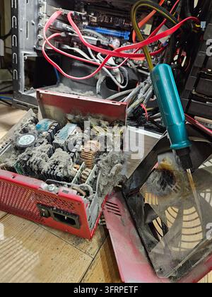 Casse con un cacciavite verde al suo interno. Il cacciavite viene utilizzato per rimuovere un componente bruciato. Polvere sull'alimentatore Foto Stock
