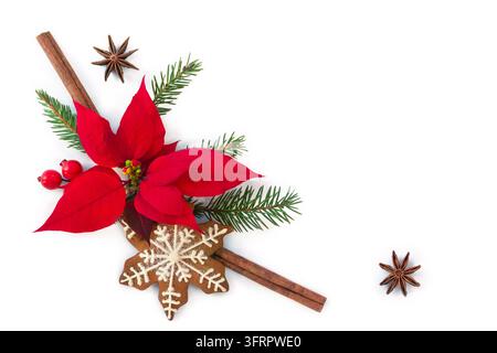Composizione piatta di decorazioni natalizie festive con vivace poinsettia rossa, anice stellato, bastoncini di cannella, biscotti allo zenzero a forma di fiocco di neve e rametti di sempreverdi su uno sfondo chiaro Foto Stock