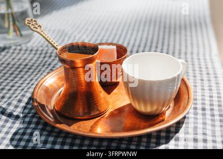 Servito su un vassoio di rame - set tradizionale di caffè turco con cezve, tazza decorata e lokum. Concetto di cultura del caffè. Foto Stock