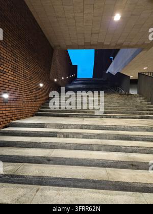 Scalinata con un muro di mattoni sullo sfondo. I gradini sono in pietra e sono illuminati da luci Foto Stock