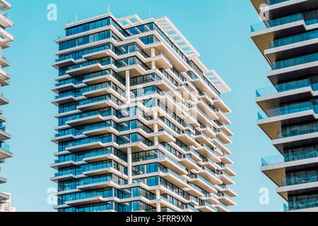 Grattacielo residenziale moderno con molti balconi e finestre in vetro, che rappresenta la vita urbana, l'architettura e il design contemporaneo Foto Stock