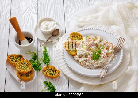 Deliziosa insalata di verdure con noodles ricoperta di condimento cremoso con carote a julienne e piselli servita con pane tostato su tavolo bianco, orizzontale Foto Stock