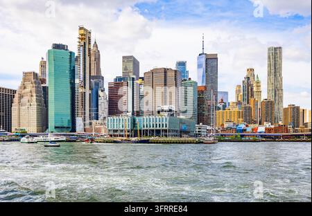 New York, USA - 25 settembre 2026: grattacieli del distretto finanziario e Pier 17 lungo il lungofiume dell’East River con barche Foto Stock