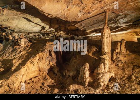 Un'illuminazione artificiale calda rivela stalattiti, stalagmiti e formazioni calcaree frastagliate lungo un passaggio sotterraneo nella Grotta Cascade a Carter Caves Foto Stock
