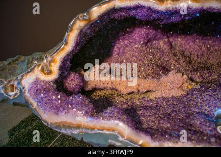 Geode di ametista con cristalli di quarzo viola che rivestono una cavità di calcedonio e agata; fotografia ravvicinata di un campione minerale. Foto Stock