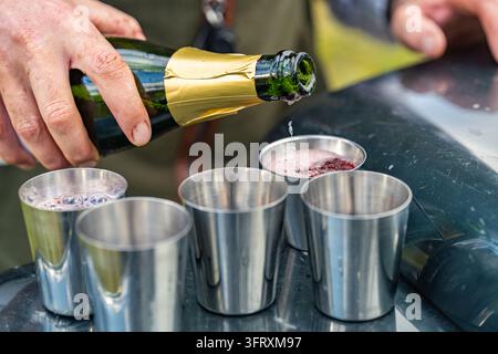 Versare vino frizzante sul gin alle prugne in bicchieri d'acciaio sul cofano di un veicolo per l'elevenses durante una caccia, Rottal Lodge, Angus, Scozia, Regno Unito Foto Stock