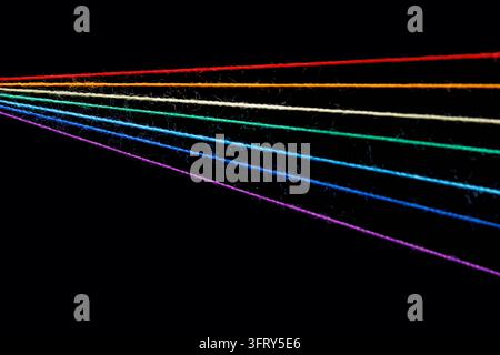 fili di cucito multicolori a forma di arcobaleno su sfondo nero in primo piano Foto Stock