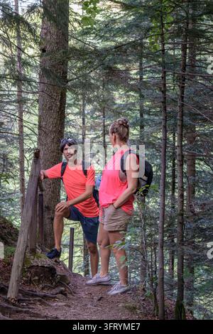 Coppia di turisti che fa una breve pausa su un sentiero boschivo di montagna sulla strada per la cascata di Maniava, Carpazi, Ucraina. Concetto di stile di vita attivo Foto Stock
