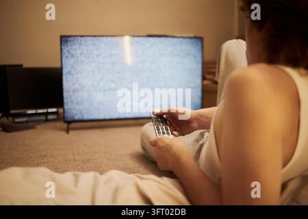 Uomo adulto che tiene il telecomando rivolto verso le statiche della televisione Foto Stock