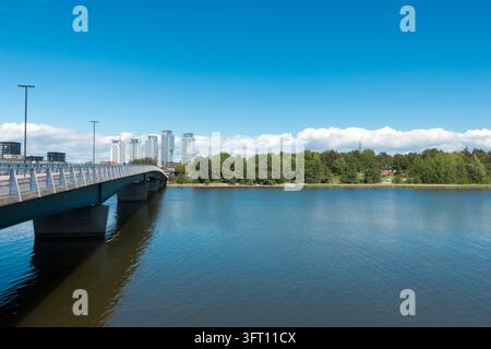 Una vista del ponte Korkeasaarensilta che collega l'isola di Korkeasaari su acque calme a Helsinki, in Finlandia, in una giornata luminosa e soleggiata Foto Stock