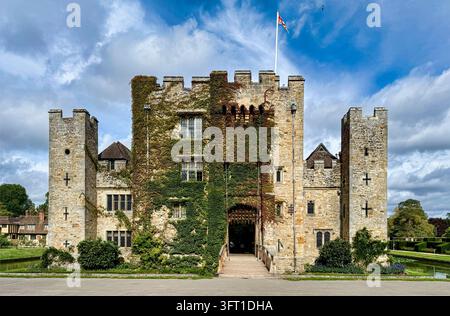 Hever Castle nel Kent, Inghilterra, castello medievale storico circondato da un fossato, con mura in pietra ricoperte di edera, torri e una bandiera Union Jack. Foto Stock