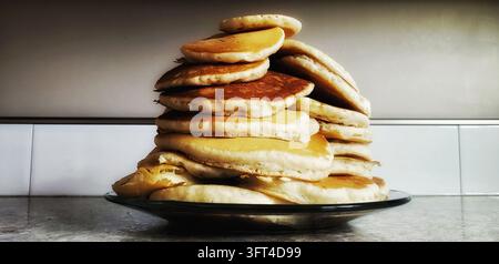 Grande pila di pancake soffici dorati ammucchiati alti su un piatto da portata Foto Stock