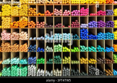 Ampia gamma di pennarelli artistici colorati disposti per tonalità in scaffali di legno nel negozio di cartoleria, vivace tavolozza arcobaleno di forniture per il disegno Foto Stock