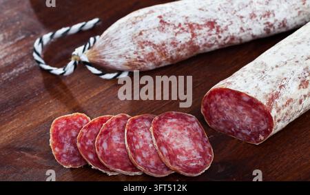 Salsiccia catalana essiccata Longaniza tradizionale con fette su tavola di legno.. Foto Stock