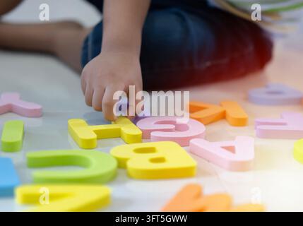 Messa a fuoco selettiva. Bambino che impara le lettere dell'alfabeto sul pavimento a casa. Concetto di gioco intellettuale per l'educazione prescolare primaria. Foto Stock