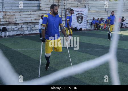 Gaza, Territori Palestinesi. 13 ott., 2026. Un calciatore con una maglia blu e pantaloncini gialli cammina sulle stampelle vicino a una rete da goal mentre i compagni si radunano lungo la linea di touche allo stadio Palestine di Gaza City, Striscia di Gaza, il 13 ottobre 2026. La partita a cinque tra la squadra del Nord e Gaza Al-Irada (Gaza Will) includeva giocatori che avevano perso arti durante la guerra a Gaza o in altri incidenti. (Foto di Eyad Azam/Middle East Images/Sipa USA) Credit: Sipa USA/Alamy Live News Foto Stock