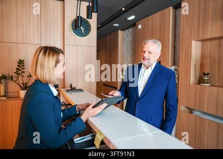 Uomo d'affari che fa il check-in alla reception dell'hotel Foto Stock