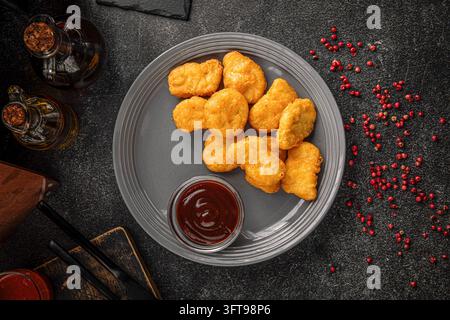 Nuggets di pollo con salsa su piatto grigio Foto Stock