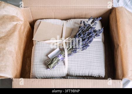 Set di garza di cotone piegato con carta kraft vuota sotto il nastro e lavanda essiccata all'interno del pacco, pronto per aggiungere un messaggio regalo personalizzato Foto Stock