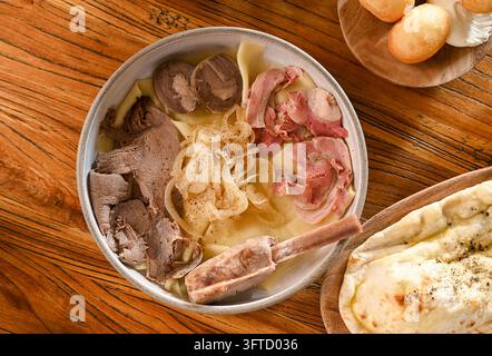 Beshbarmak kazako tradizionale con carne bollita, noodles e cipolle su tavolo di legno Foto Stock