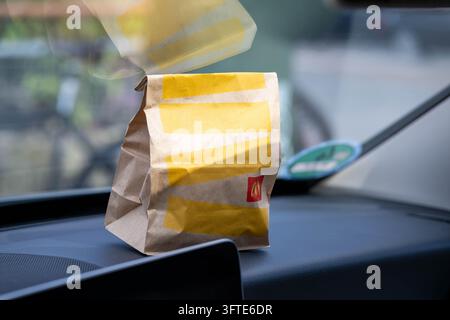 Un sacchetto di carta McDonald's sul cruscotto di un'auto dietro il parabrezza. Immagine simbolica per il fast food e il mangiare in movimento. Schifferstadt, Germania, 11 Se Foto Stock