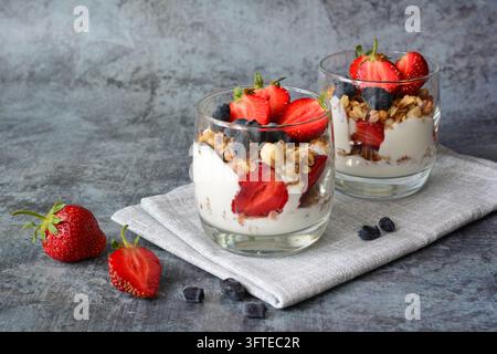 Parfait allo yogurt con fragole e mirtilli con granola su tavolo di pietra, spazio per il testo Foto Stock
