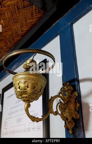 Apparecchio da parete vintage in ottone antico montato su muro bianco e blu con soffitto in bambù intrecciato Foto Stock