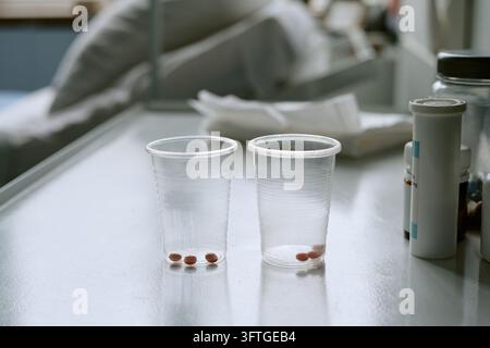 Compresse di farmaci prescritti in bicchieri di plastica per l'assistenza ai pazienti ospedalieri Foto Stock
