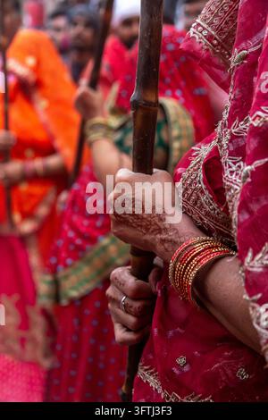 Primo piano di una donna in un sari rosso ricamato che tiene un bastone di legno (lathi) durante il Lathmar Holi, Uttar Pradesh, Barsana, India Foto Stock