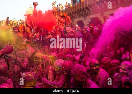 Folla coperta di polvere rosa e rossa con colore volante a Braj Ki Holi, Uttar Pradesh, Nandgaon, India Foto Stock