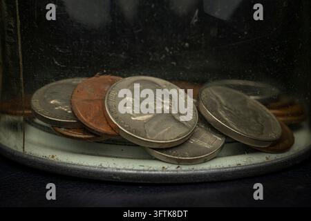 Primo piano di monete statunitensi tra cui nichelini e penny conservati in un barattolo di vetro trasparente per le mance o un salvadanaio Foto Stock