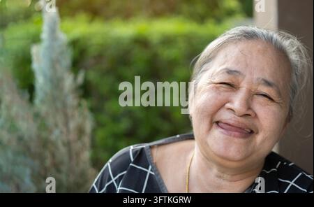 Ritratto ravvicinato di una gentile anziana asiatica che sorride alla telecamera a casa, spazio per il testo Foto Stock