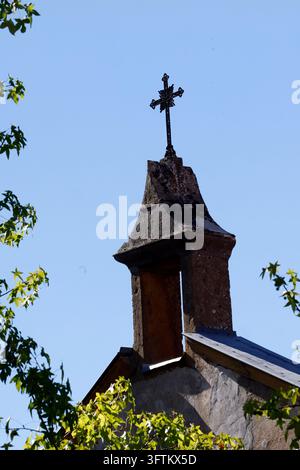Campanile in pietra sormontato da una croce in metallo.  Cappella cattolica.  Francia. Foto Stock