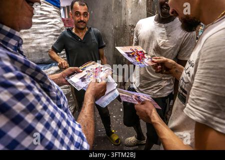 Uomini osservano stampe fotografiche nel quartiere dei raccoglitori di stracci di Moqattam al Cairo, in Egitto. Foto Stock