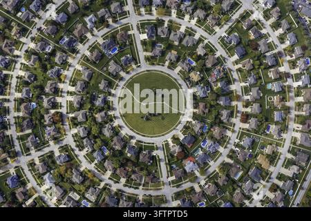 Vista aerea di un quartiere residenziale circolare con case di periferia, prati curati, piscine e un parco verde centrale nell'Illinois, Stati Uniti Foto Stock