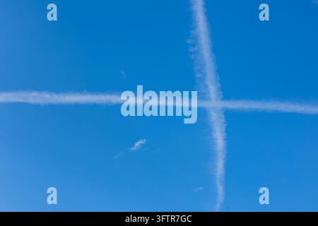Tracciamenti di jet incrociati che formano una croce bianca su un cielo blu terso Foto Stock