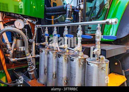Sistema idraulico industriale con manometro, valvole di controllo in acciaio inossidabile, tubi intrecciati e serbatoi di fluido sulle macchine Foto Stock
