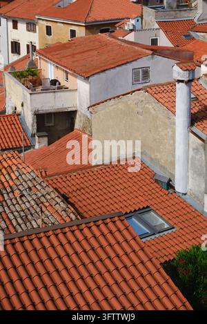 Prima vista ad angolazione alta su tegole tradizionali in terracotta e camini nella vecchia città di Pirano, Slovenia. Foto Stock