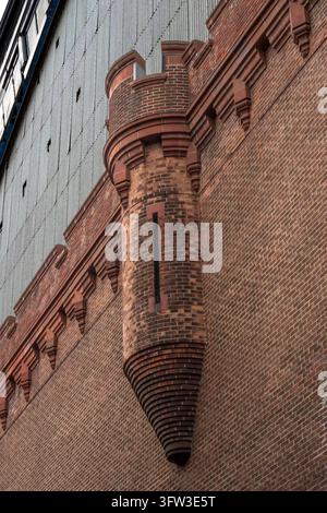 Bronx, NY - USA - 17 ott 2026: Una stretta torretta in mattoni sporge dal muro laterale dell'Armeria di Kingsbridge, terminando con una base a mensola appuntita sottost Foto Stock