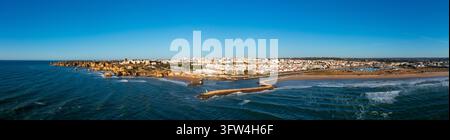 La città di Lagos si estende lungo la costa con oceano, spiaggia, frangiflutti del porto e edifici bassi. Foto Stock