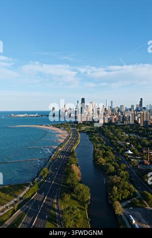 Vista aerea verticale di Lake Shore Drive tra il lago Michigan e una laguna del parco verso lo skyline del centro città in una serata soleggiata, Chicago, Illinois Foto Stock